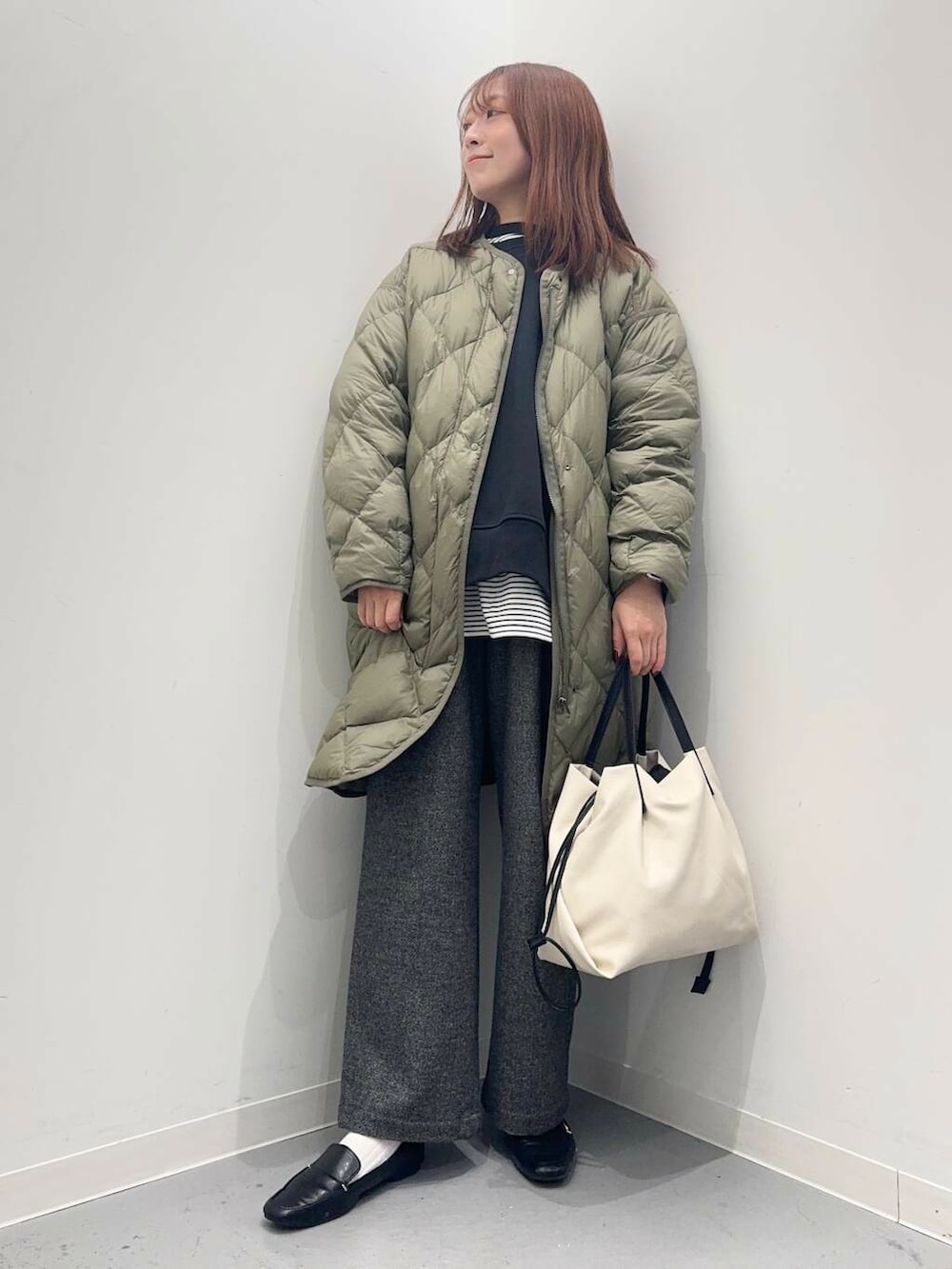 ブラック系のローファー、ホワイト系のショルダーバッグ、グリーン系のダウンジャケット/コートを着用したレディースの秋コーディネートの2枚目の写真
