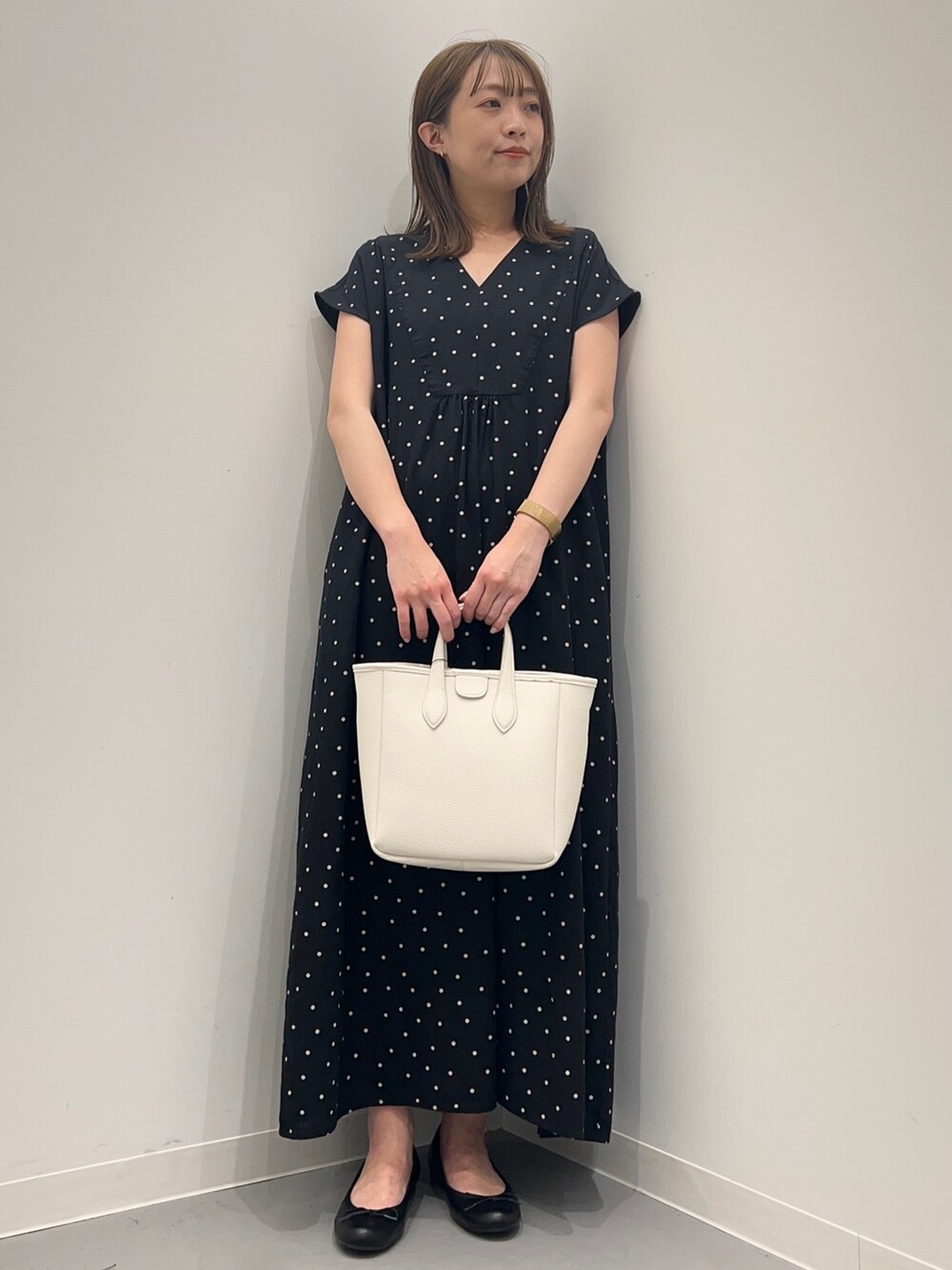 ブラック系のワンピース、ホワイト系のトートバッグを着用したレディースの春コーディネートの2枚目の写真