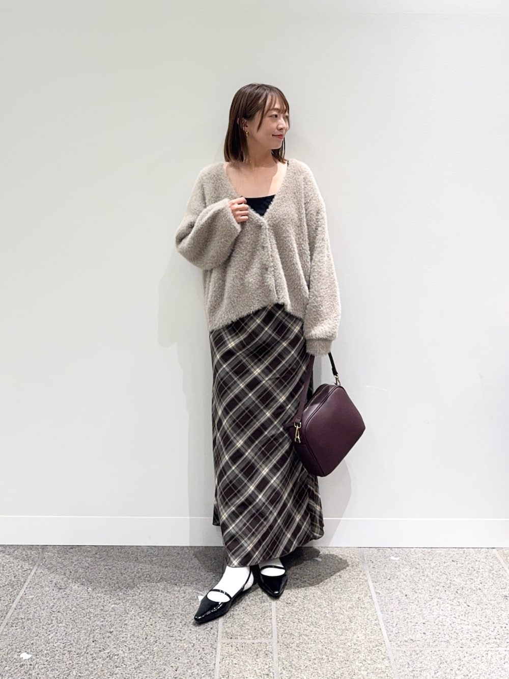 ベージュ系のカーディガン/ボレロ、ブラウン系のスカート、レッド系のショルダーバッグを着用したレディースの秋コーディネートの2枚目の写真