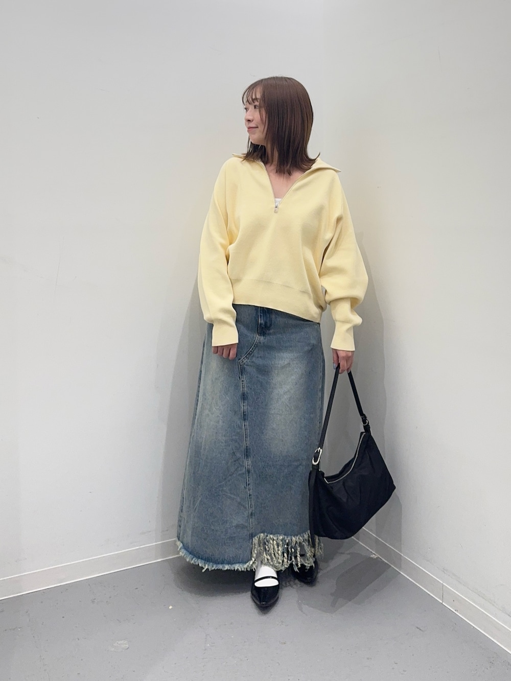 イエロー系のスウェット、ブルー系のスカート、ブラック系のショルダーバッグを着用したレディースの冬コーディネートの4枚目の写真