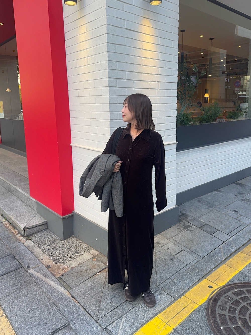 ブラウン系のワンピース、ブラウン系のスニーカー、ブラック系のショルダーバッグを着用したレディースの秋コーディネートの2枚目の写真