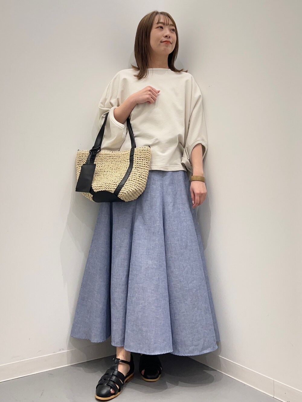 ベージュ系のTシャツ/カットソー、ブルー系のスカート、ブラック系のサンダルを着用したレディースの春コーディネートの3枚目の写真