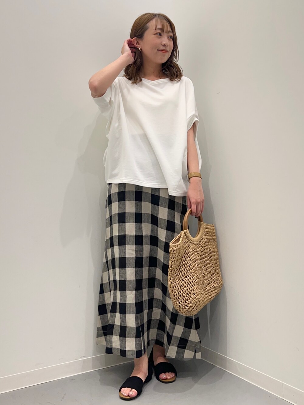 ホワイト系のTシャツ/カットソー、ブラック系のスカート、ベージュ系のかごバッグを着用したレディースの春コーディネートの2枚目の写真