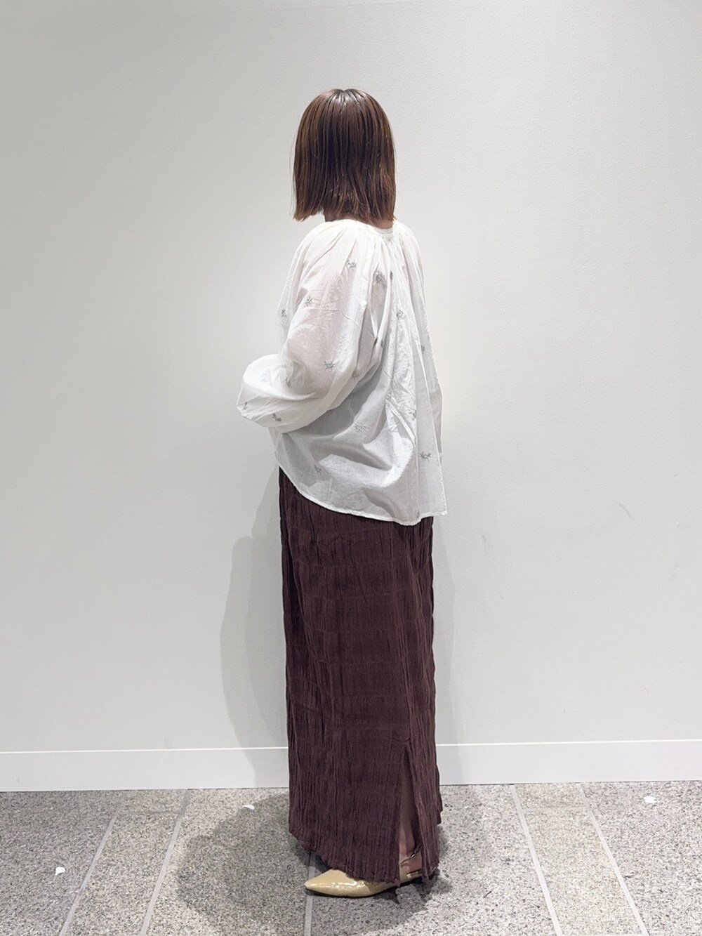 ホワイト系のシャツ/ブラウス、ブラウン系のスカート、ベージュ系のパンプスを着用したレディースの秋コーディネートの3枚目の写真