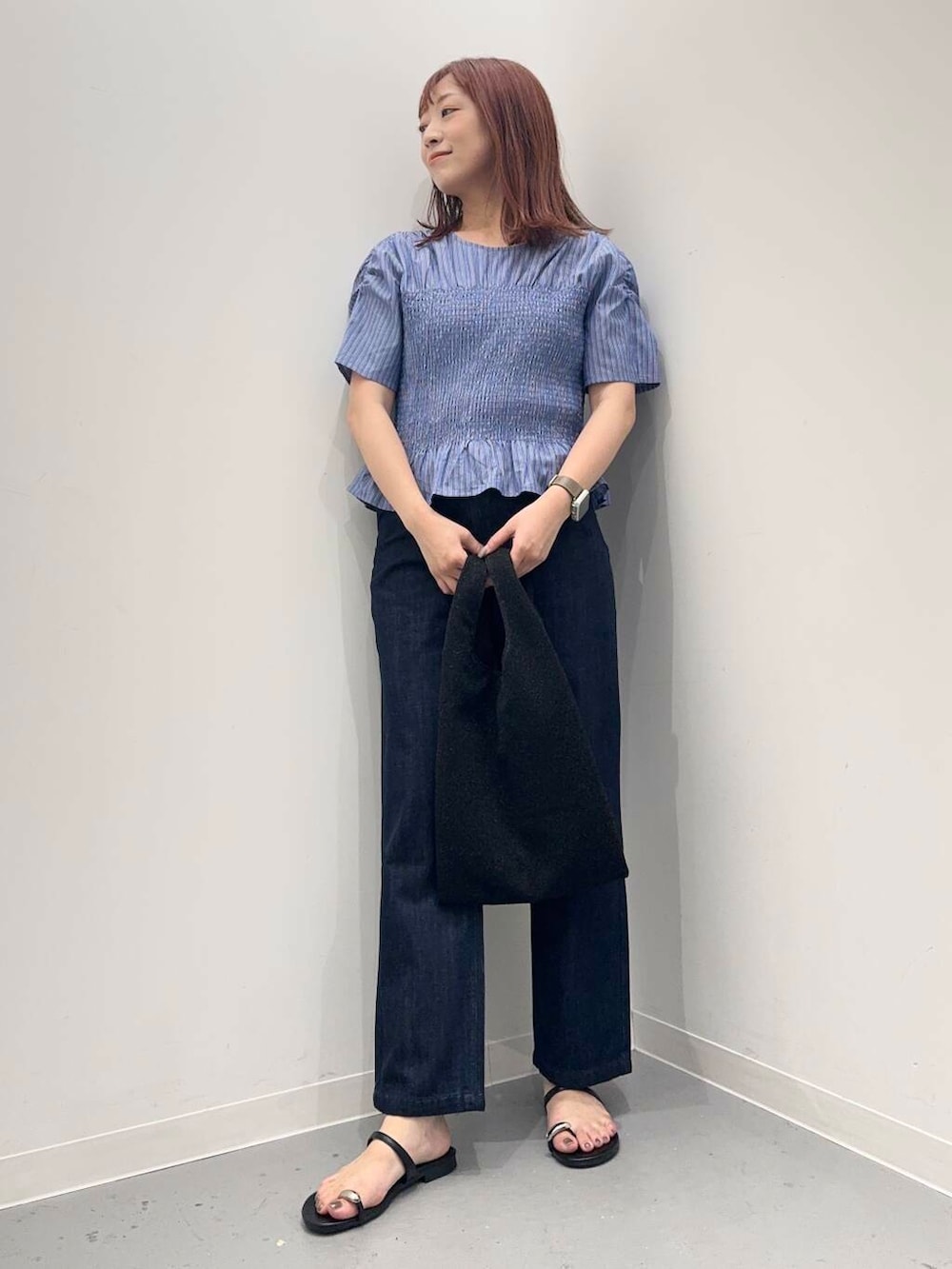 ブルー系のデニムパンツ、ブラック系のサンダル、ブラック系のトートバッグを着用したレディースの夏コーディネートの2枚目の写真
