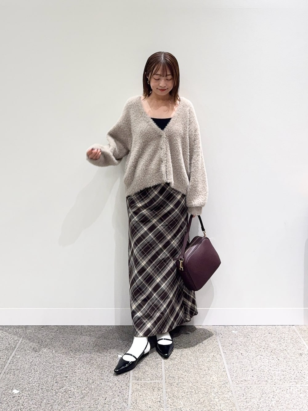 ベージュ系のカーディガン/ボレロ、ブラウン系のスカート、レッド系のショルダーバッグを着用したレディースの秋コーディネートの5枚目の写真