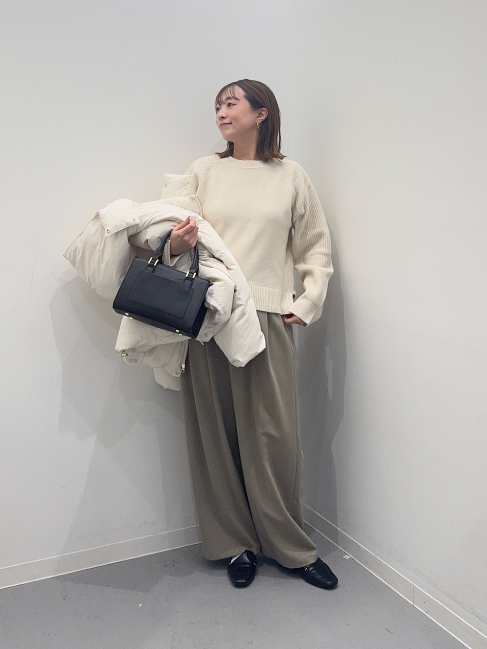 ホワイト系のダウンジャケット/コート、ベージュ系のその他パンツ、ブラック系のハンドバッグを着用したレディースの冬コーディネートの4枚目の写真