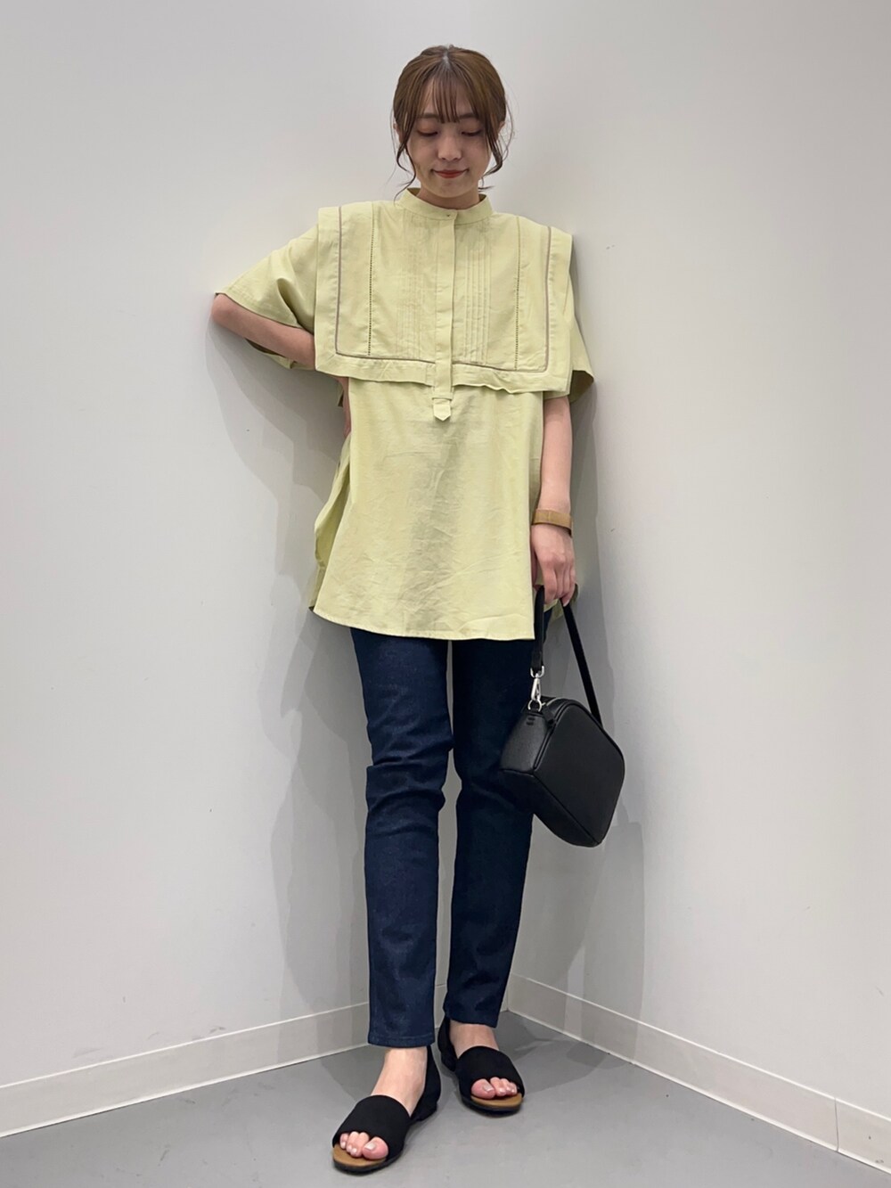 イエロー系のシャツ/ブラウス、ブルー系のデニムパンツ、ブラック系のショルダーバッグを着用したレディースの春コーディネートの2枚目の写真