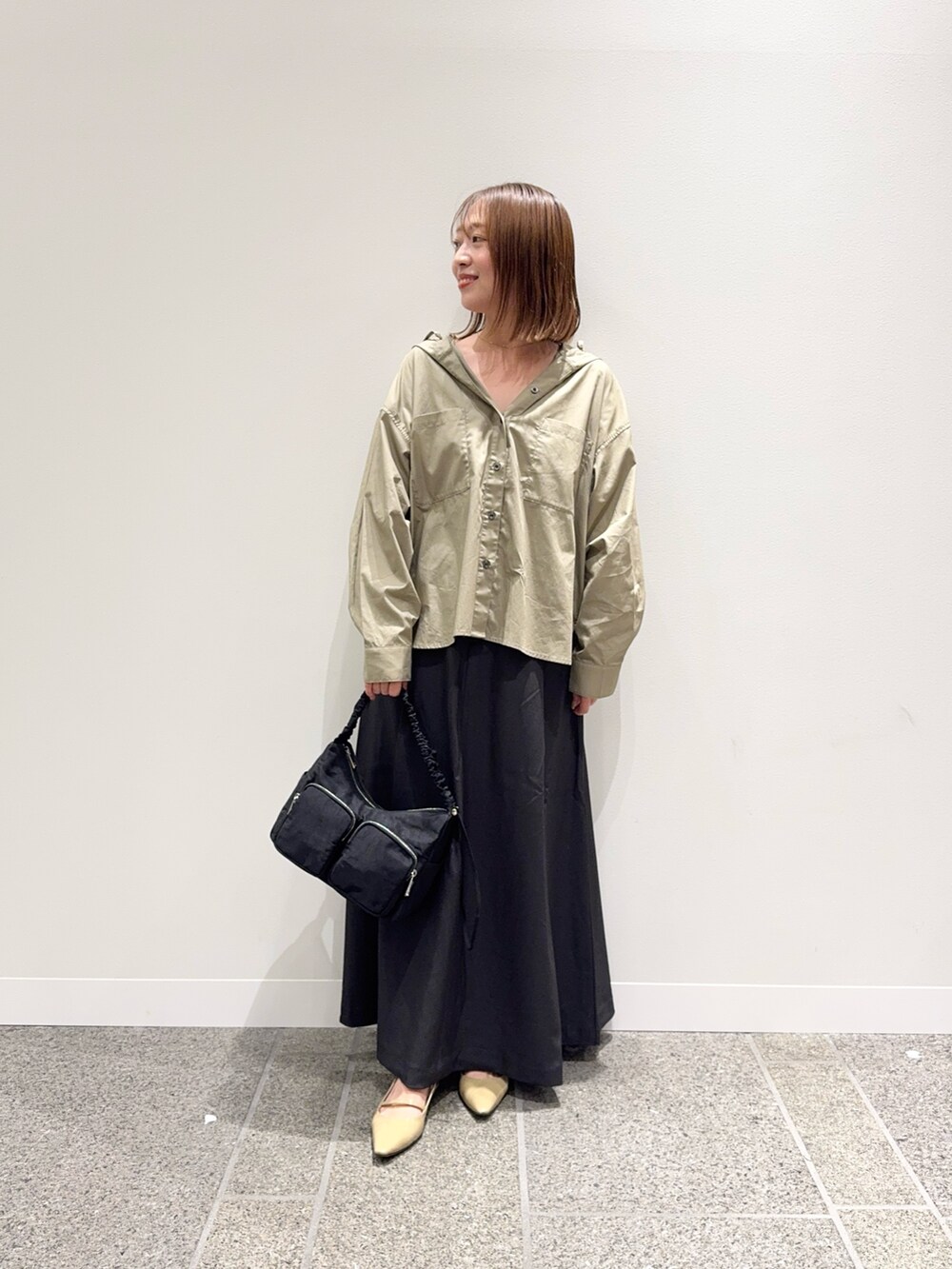 ベージュ系のシャツ/ブラウス、グレー系のスカート、ベージュ系のパンプスを着用したレディースの秋コーディネートの6枚目の写真