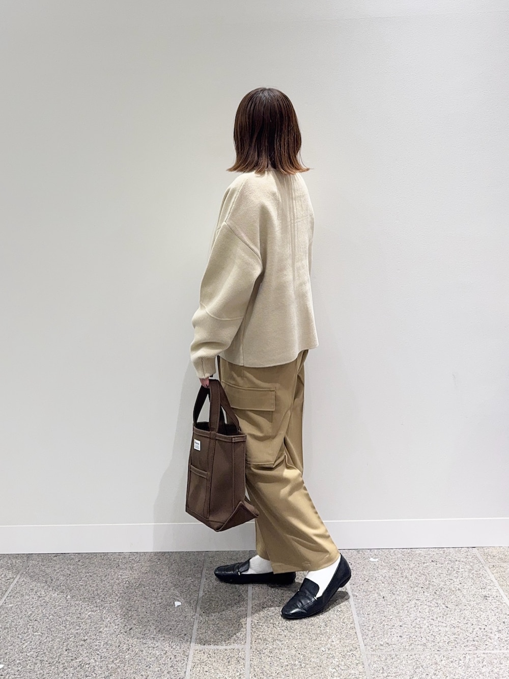 ベージュ系のニット/セーター、ホワイト系のTシャツ/カットソー、ブラウン系のトートバッグを着用したレディースの秋コーディネートの3枚目の写真