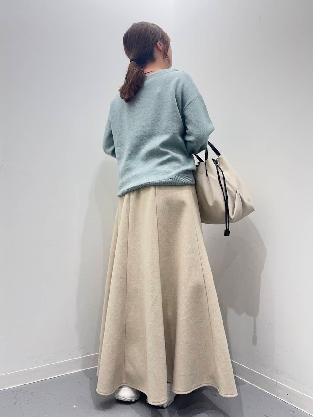 ホワイト系のショルダーバッグ、ホワイト系のスニーカー、グリーン系のニット/セーターを着用したレディースの冬コーディネートの4枚目の写真