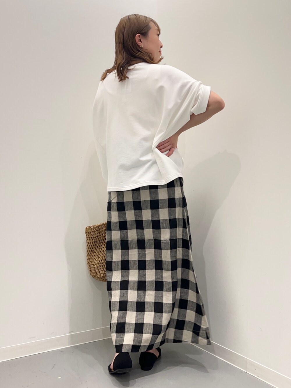 ホワイト系のTシャツ/カットソー、ブラック系のスカート、ベージュ系のかごバッグを着用したレディースの春コーディネートの5枚目の写真