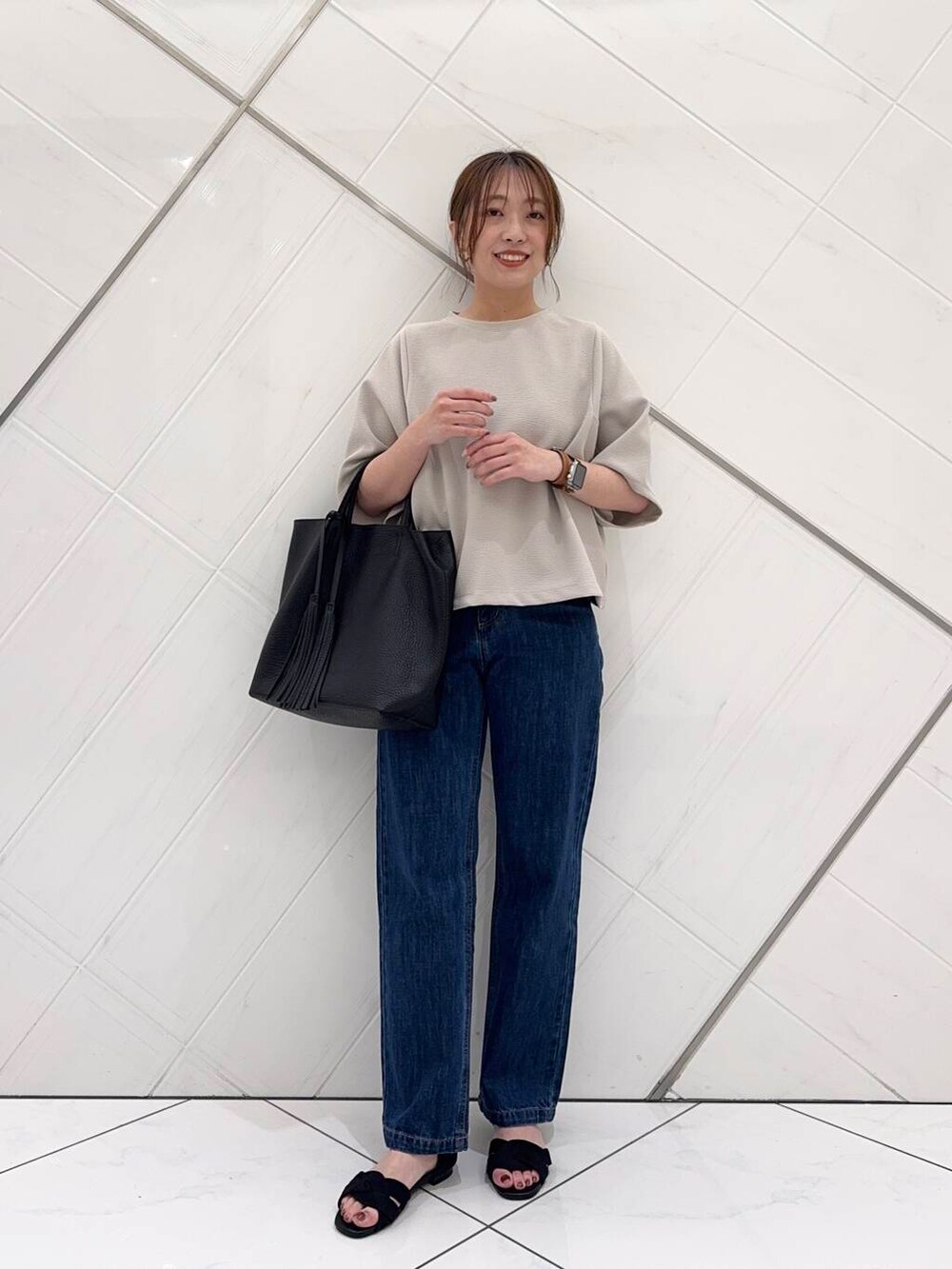 ブルー系のデニムパンツ、ブラック系のトートバッグ、ブラック系のサンダルを着用したレディースの春コーディネートの6枚目の写真