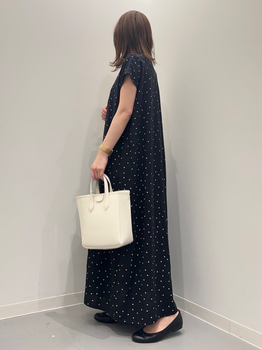 ブラック系のワンピース、ホワイト系のトートバッグを着用したレディースの春コーディネートの3枚目の写真