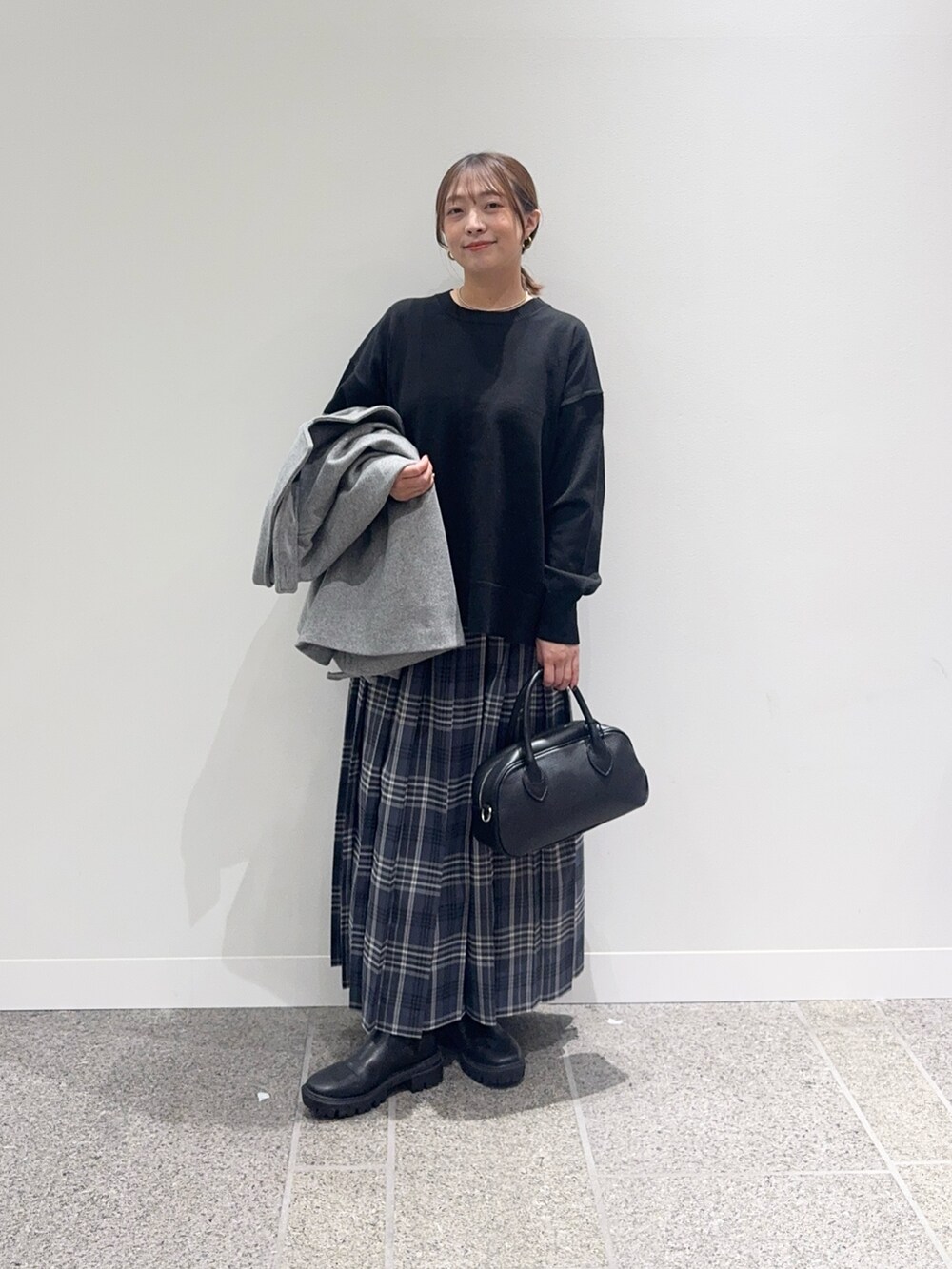 グレー系のその他アウター、ブラック系のニット/セーター、グレー系のスカートを着用したレディースの秋コーディネートの7枚目の写真