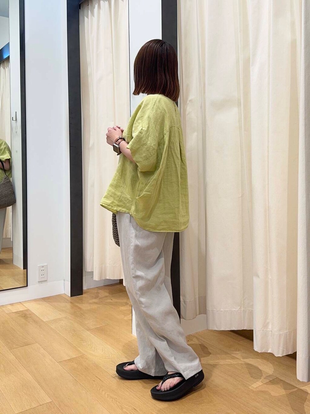 グレー系のトートバッグ、ブラック系のサンダル、イエロー系のシャツ/ブラウスを着用したレディースの夏コーディネートの3枚目の写真