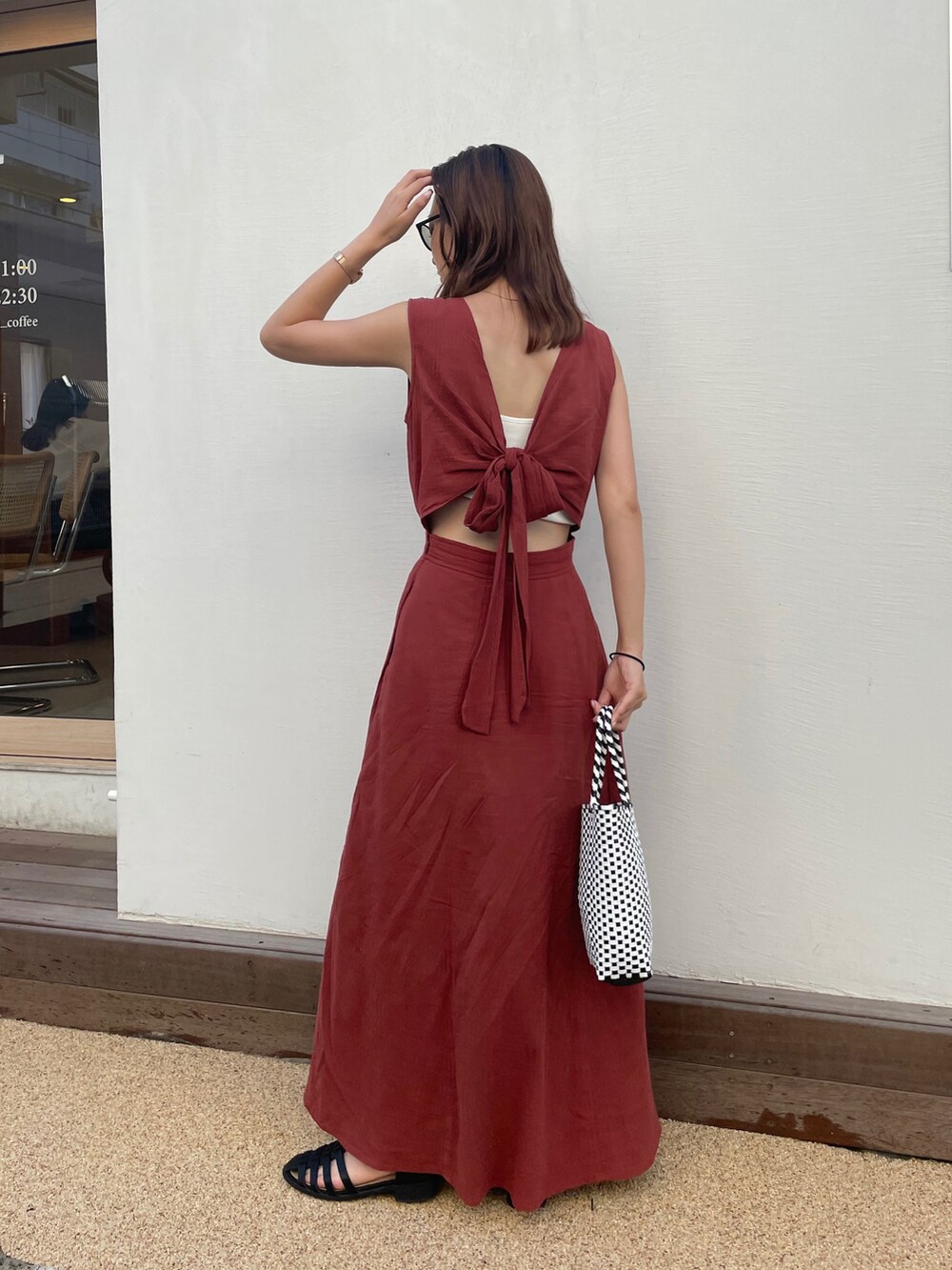 オレンジ系のワンピース、ブラック系のかごバッグ、ブラック系のサンダルを着用したレディースの夏コーディネートの3枚目の写真