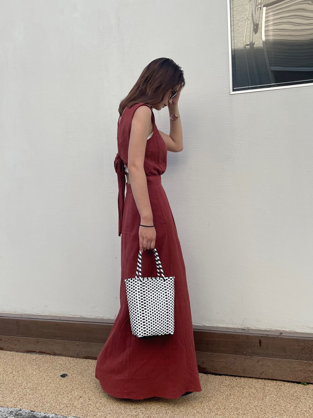 オレンジ系のワンピース、ブラック系のかごバッグ、ブラック系のサンダルを着用したレディースの夏コーディネートの4枚目の写真