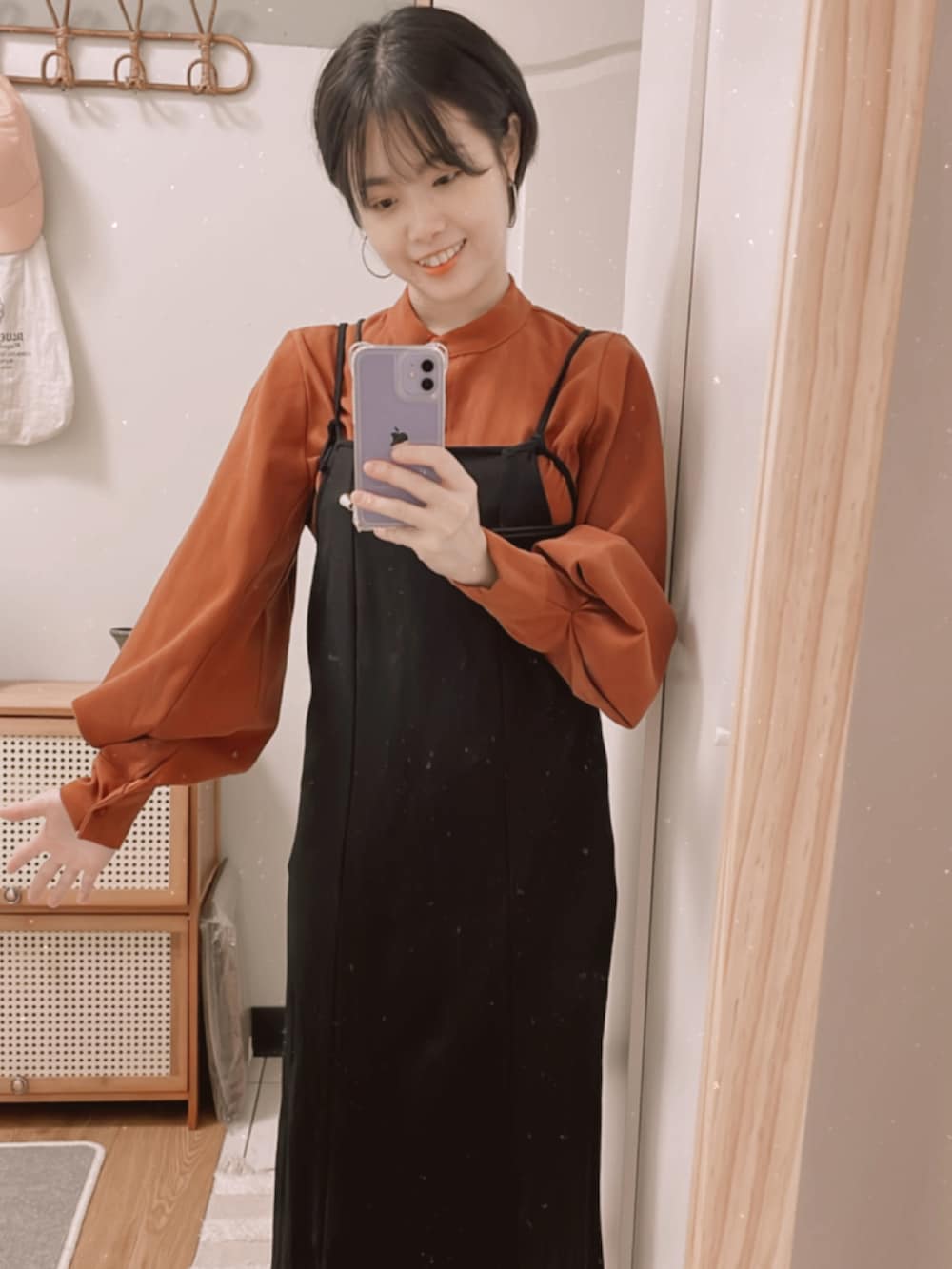 オレンジ系のシャツ/ブラウス、ブラック系のジャンパースカートを着用したレディースの秋コーディネートの3枚目の写真