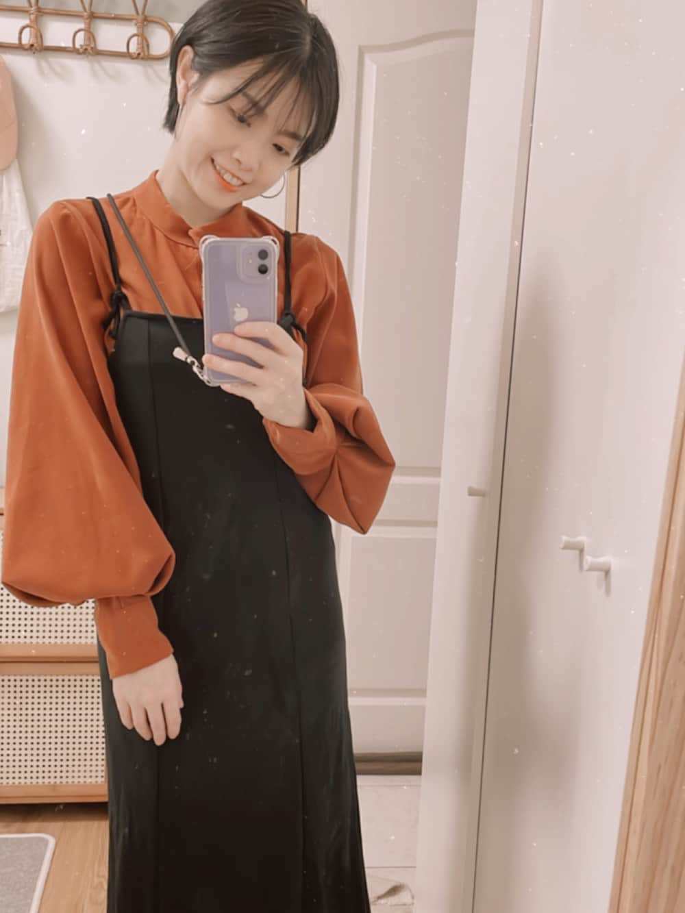 オレンジ系のシャツ/ブラウス、ブラック系のジャンパースカートを着用したレディースの秋コーディネートの2枚目の写真