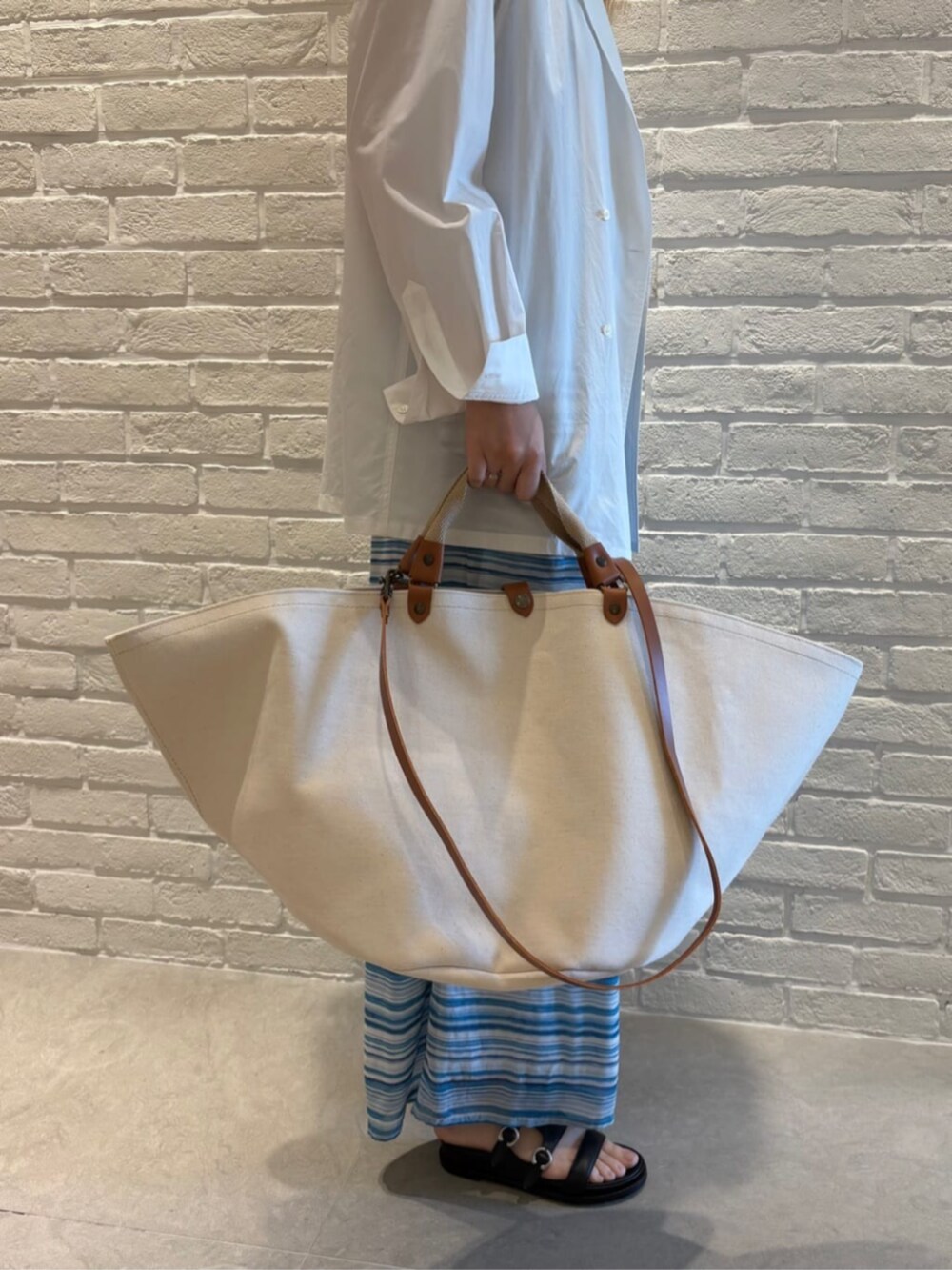 ホワイト系のテーラードジャケット、ブルー系のタンクトップ、ブルー系のその他パンツを着用したレディースの春コーディネートの5枚目の写真