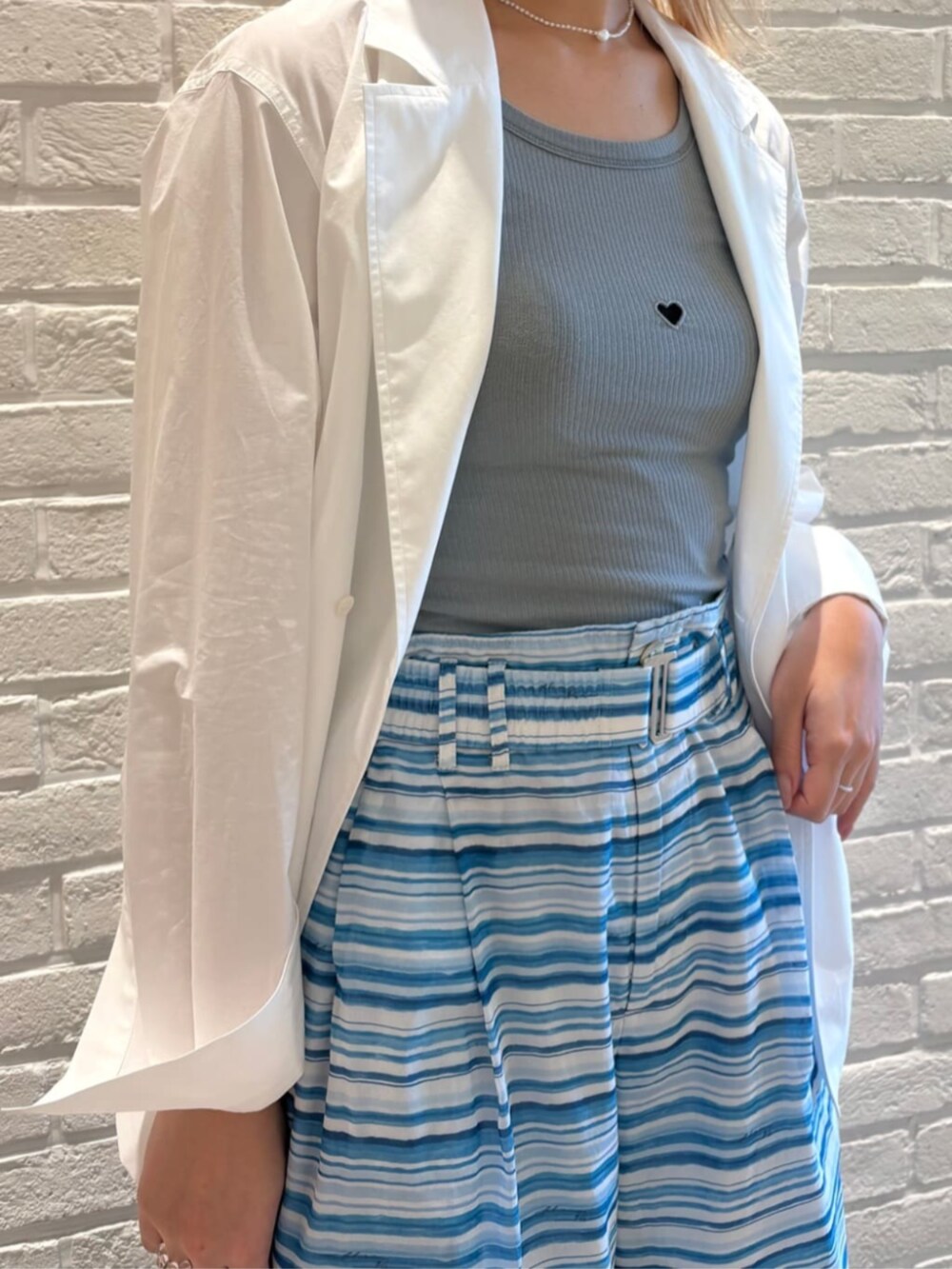 ホワイト系のテーラードジャケット、ブルー系のタンクトップ、ブルー系のその他パンツを着用したレディースの春コーディネートの3枚目の写真