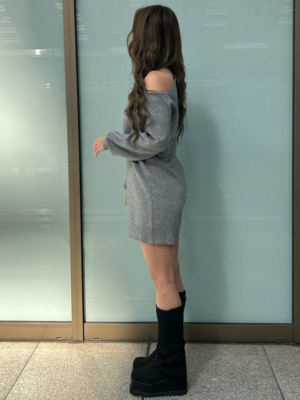 グレー系のワンピース、ブラック系のブーツを着用したレディースの冬コーディネートの2枚目の写真