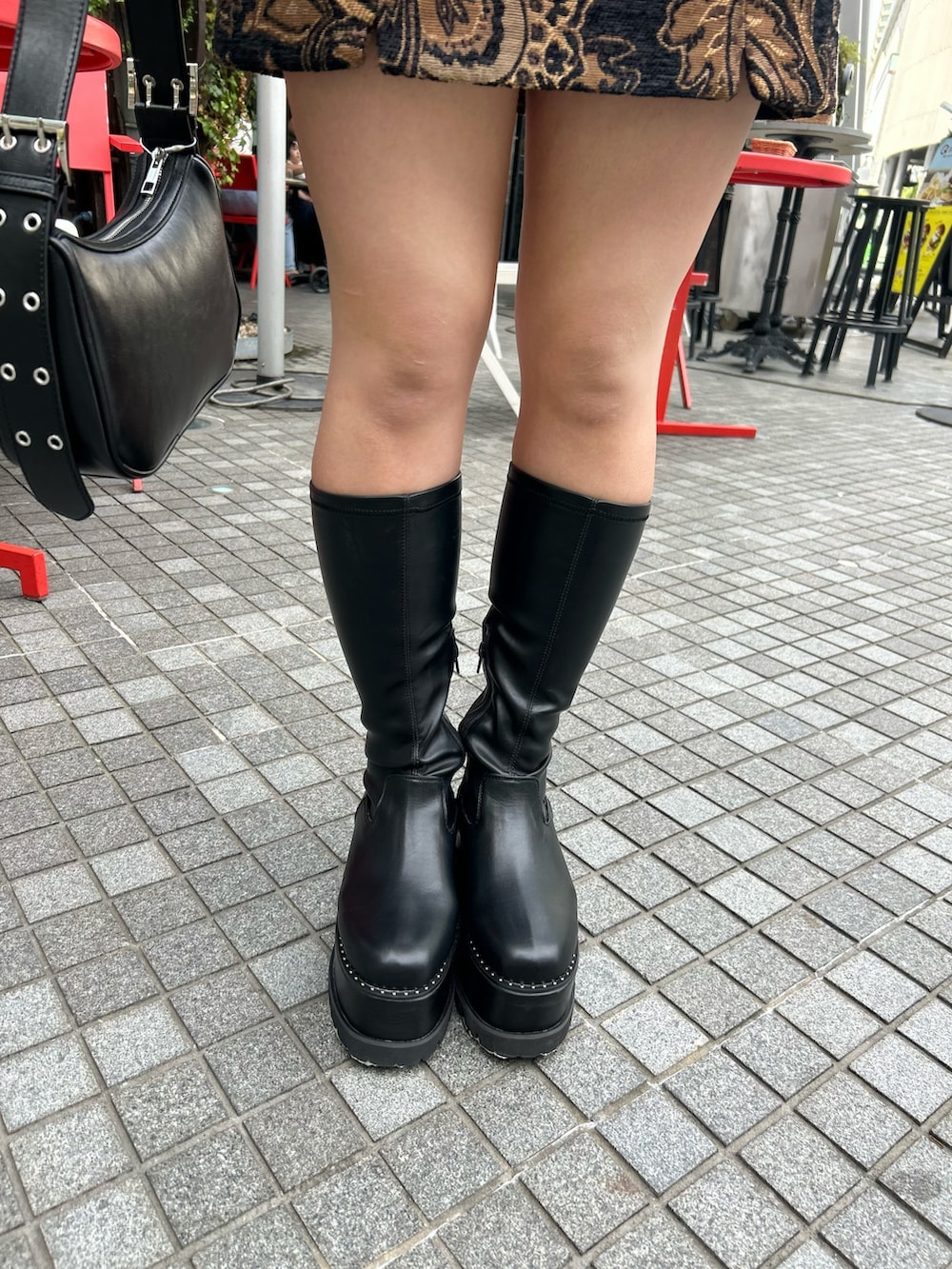 ブラック系のスカート、ブラック系のニット/セーター、ブラック系のブーツを着用したレディースの秋コーディネートの7枚目の写真
