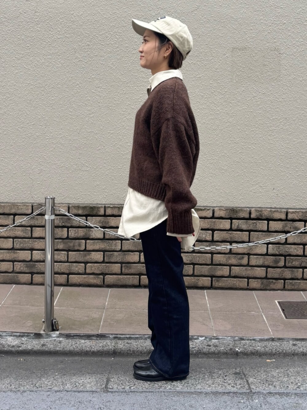 ブラウン系のニット/セーター、ホワイト系のシャツ/ブラウス、ブルー系のデニムパンツを着用したレディースの秋コーディネートの3枚目の写真