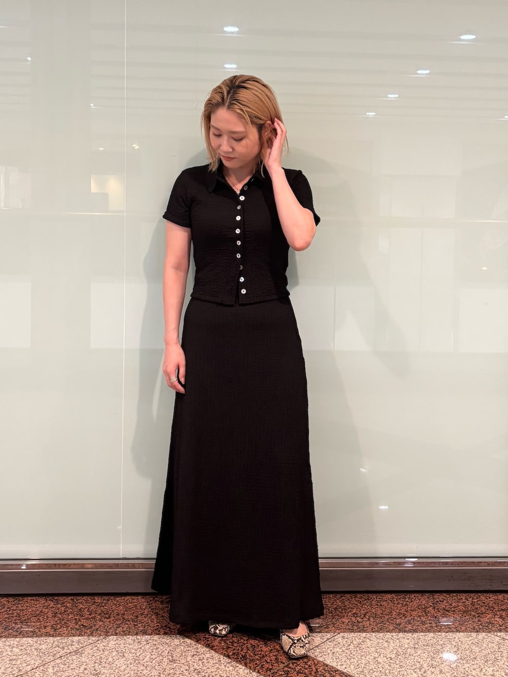 ブラック系のポロシャツ、ブラック系のスカートを着用したレディースの夏コーディネートの5枚目の写真