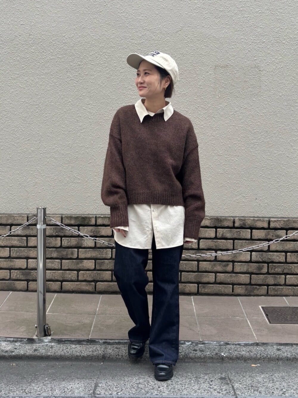 ブラウン系のニット/セーター、ホワイト系のシャツ/ブラウス、ブルー系のデニムパンツを着用したレディースの秋コーディネートの5枚目の写真