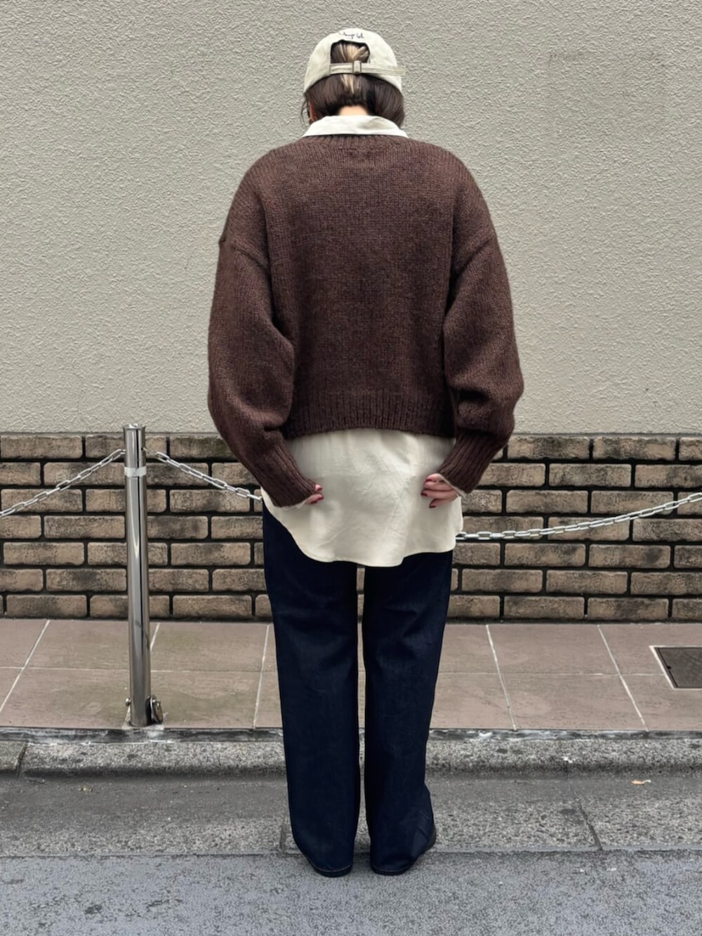 ブラウン系のニット/セーター、ホワイト系のシャツ/ブラウス、ブルー系のデニムパンツを着用したレディースの秋コーディネートの4枚目の写真