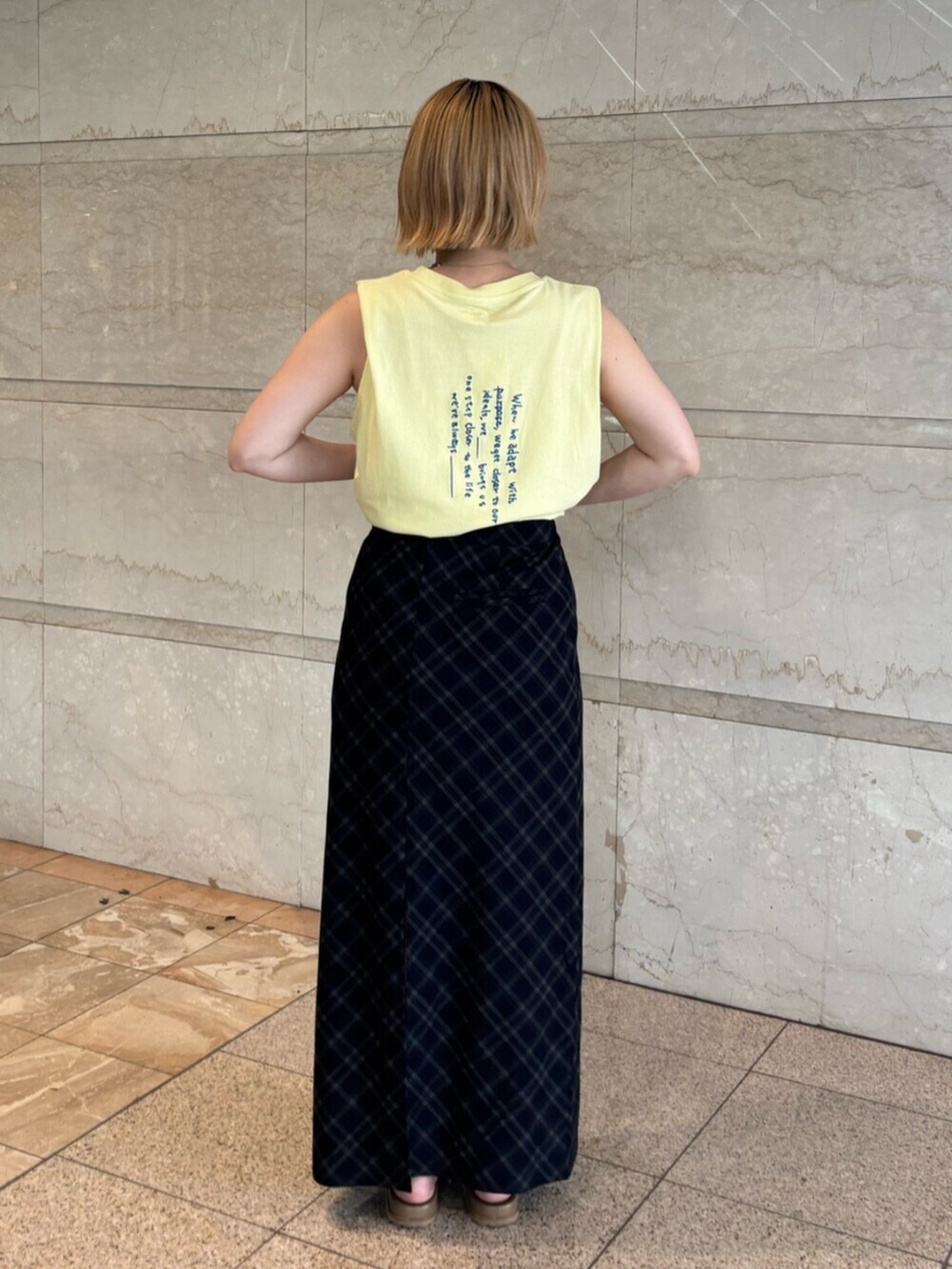 イエロー系のタンクトップ、ブルー系のスカートを着用したレディースの夏コーディネートの3枚目の写真