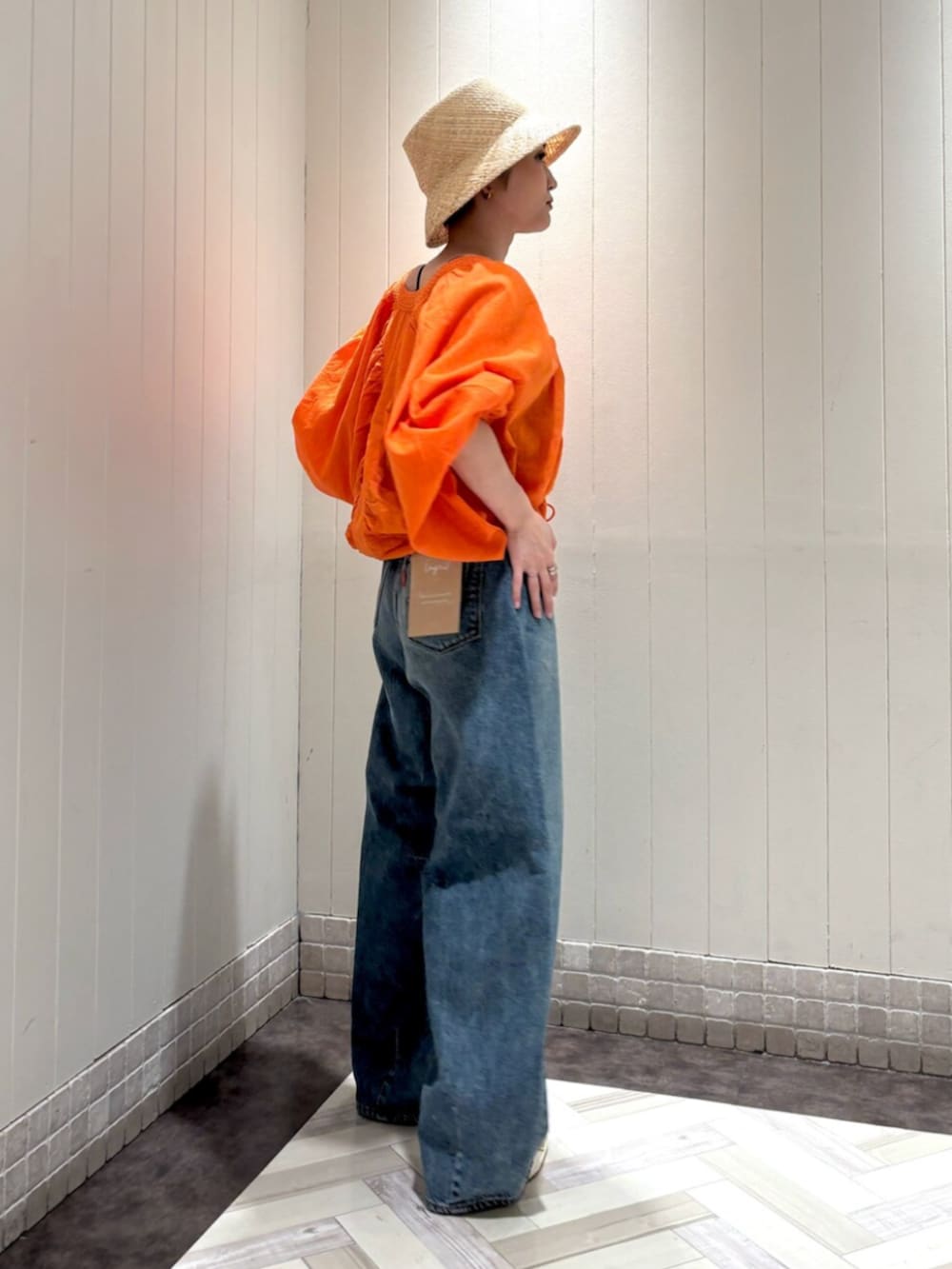 オレンジ系のシャツ/ブラウス、ブルー系のデニムパンツ、ベージュ系のハットを着用したレディースの夏コーディネートの2枚目の写真