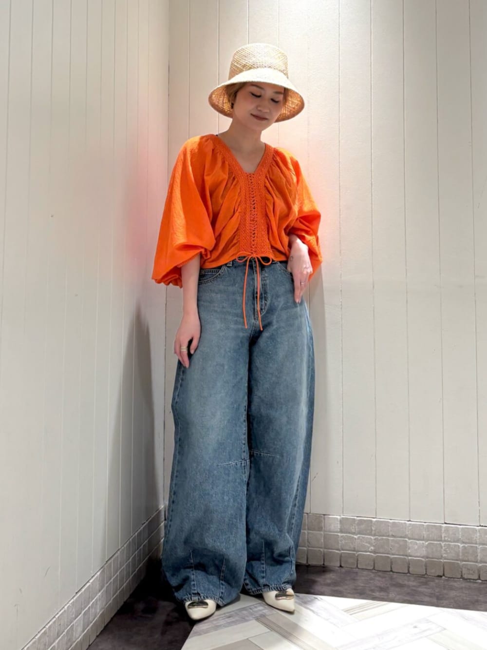 オレンジ系のシャツ/ブラウス、ブルー系のデニムパンツ、ベージュ系のハットを着用したレディースの夏コーディネートの4枚目の写真