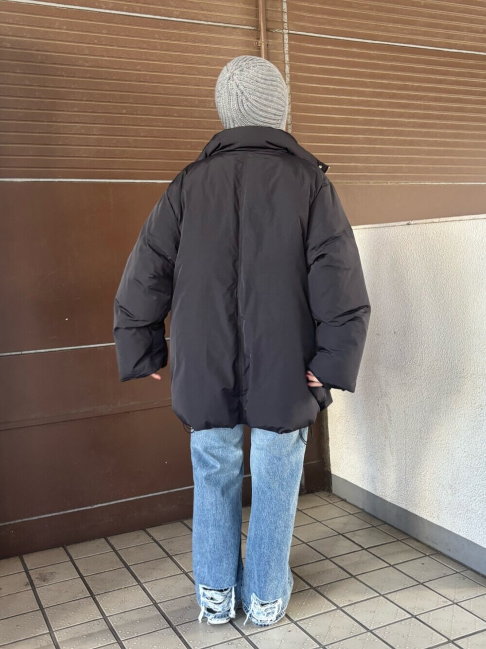 ブラック系のダウンジャケット/コート、レッド系のニット/セーター、ブルー系のデニムパンツを着用したレディースの冬コーディネートの4枚目の写真