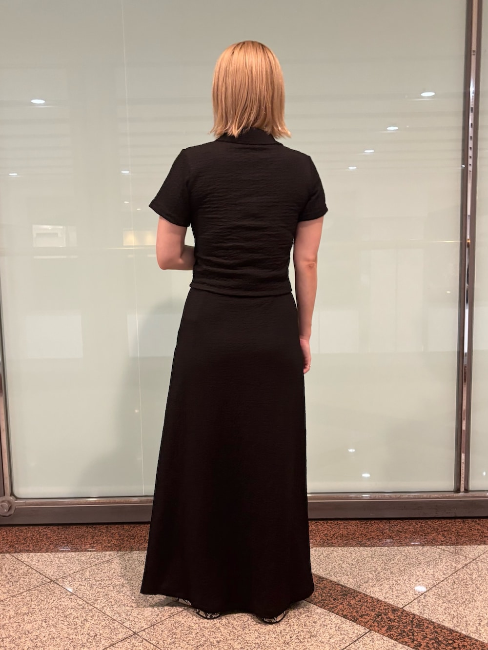 ブラック系のポロシャツ、ブラック系のスカートを着用したレディースの夏コーディネートの4枚目の写真