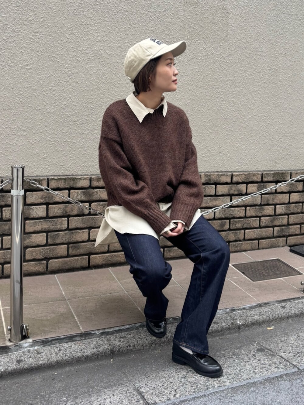 ブラウン系のニット/セーター、ホワイト系のシャツ/ブラウス、ブルー系のデニムパンツを着用したレディースの秋コーディネートの6枚目の写真