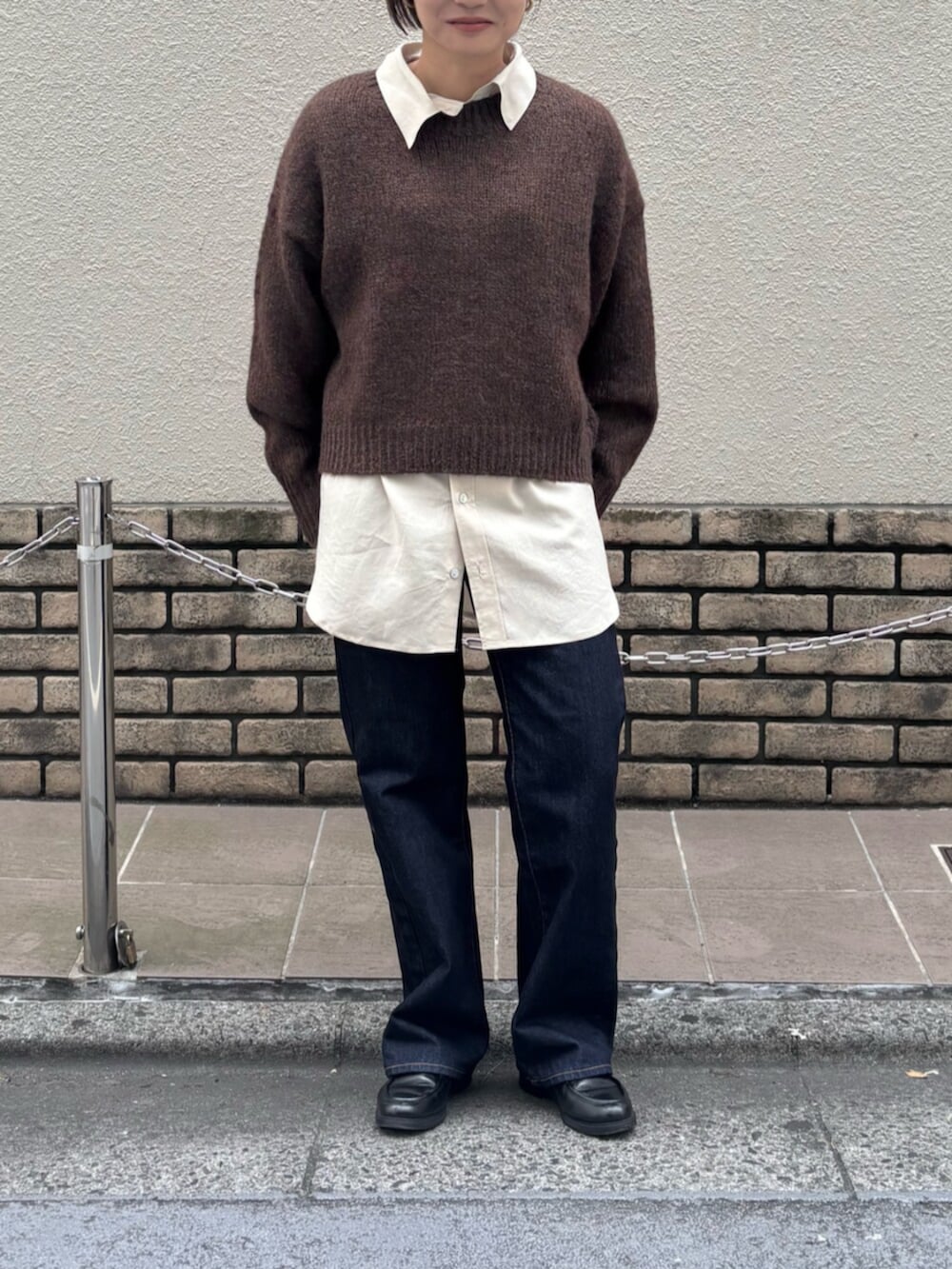 ブラウン系のニット/セーター、ホワイト系のシャツ/ブラウス、ブルー系のデニムパンツを着用したレディースの秋コーディネートの2枚目の写真