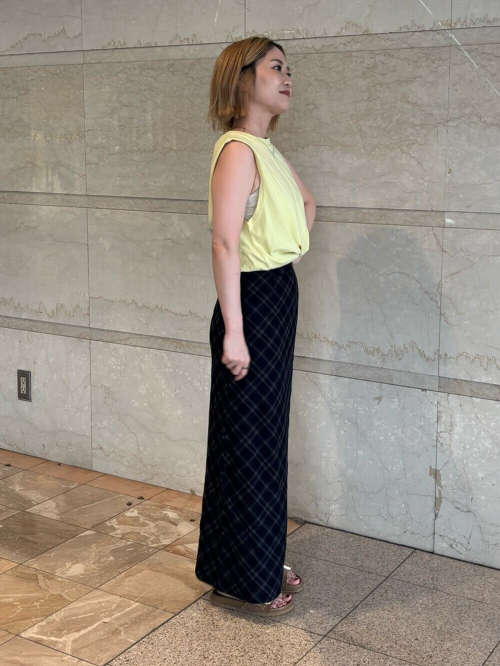 イエロー系のタンクトップ、ブルー系のスカートを着用したレディースの夏コーディネートの2枚目の写真