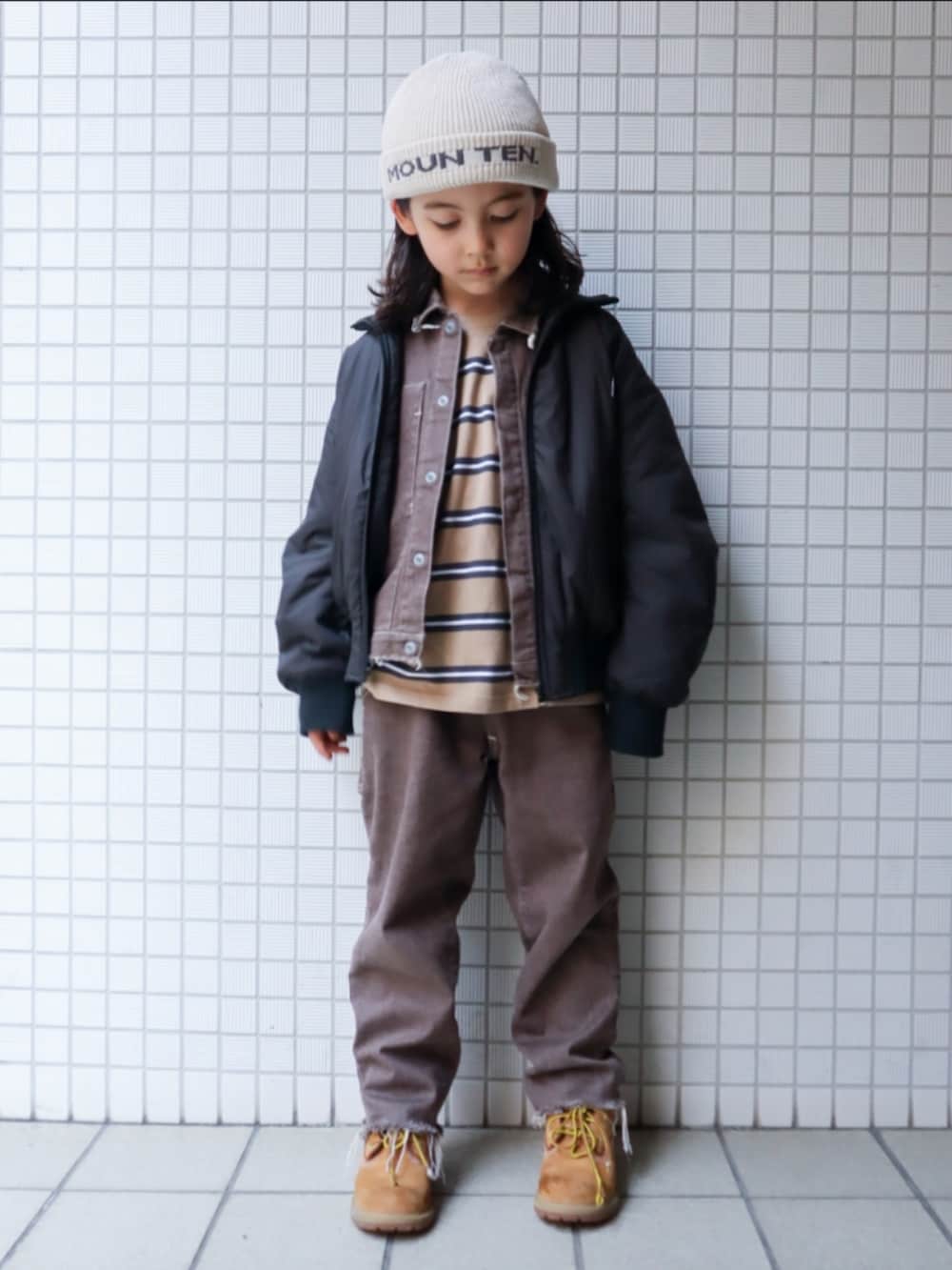 ベージュ系のブーツ、ベージュ系のTシャツ/カットソー、ブラウン系のデニムパンツを着用したキッズの冬コーディネートの2枚目の写真