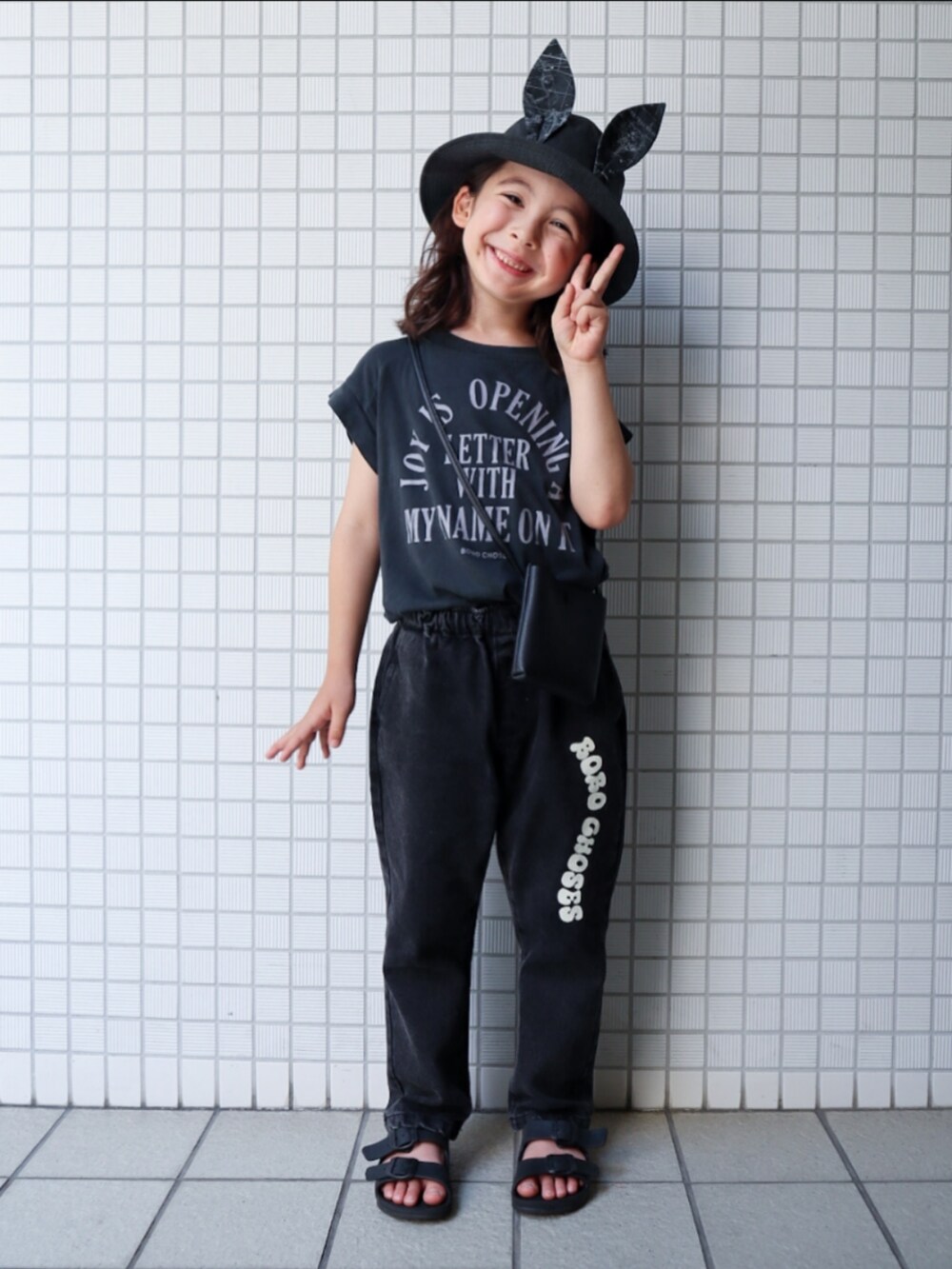 ブラック系のTシャツ/カットソー、ブラック系のデニムパンツ、ブラック系のサンダルを着用したキッズの夏コーディネートの2枚目の写真