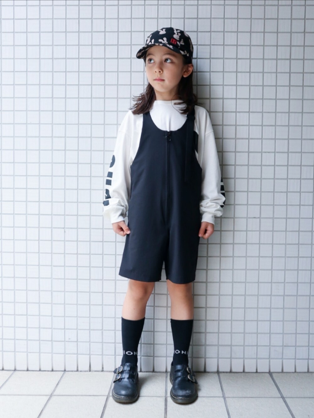 ホワイト系のTシャツ/カットソー、ブラック系のサロペット/オーバーオール、ブラック系のキャップを着用したキッズの秋コーディネートの2枚目の写真