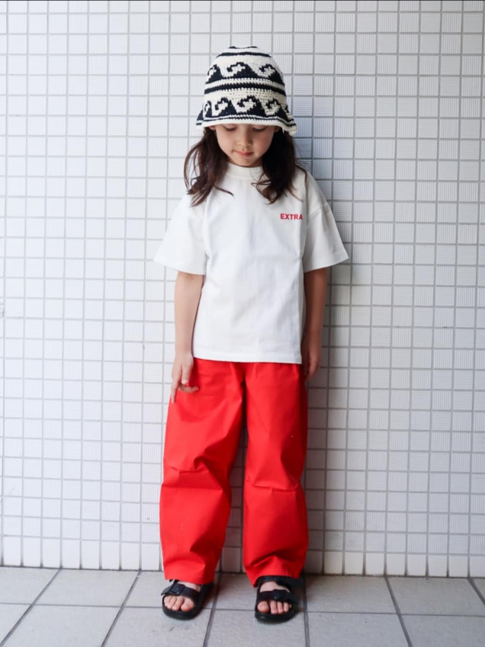 レッド系のその他パンツ、ブラック系のサンダル、ホワイト系のTシャツ/カットソーを着用したキッズの春コーディネートの2枚目の写真