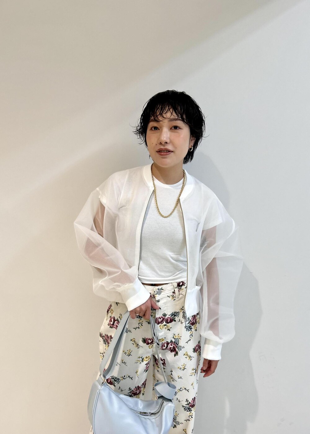 ブルー系のショルダーバッグ、ホワイト系のカーディガン/ボレロ、ベージュ系のデニムパンツを着用したレディースの春コーディネートの4枚目の写真