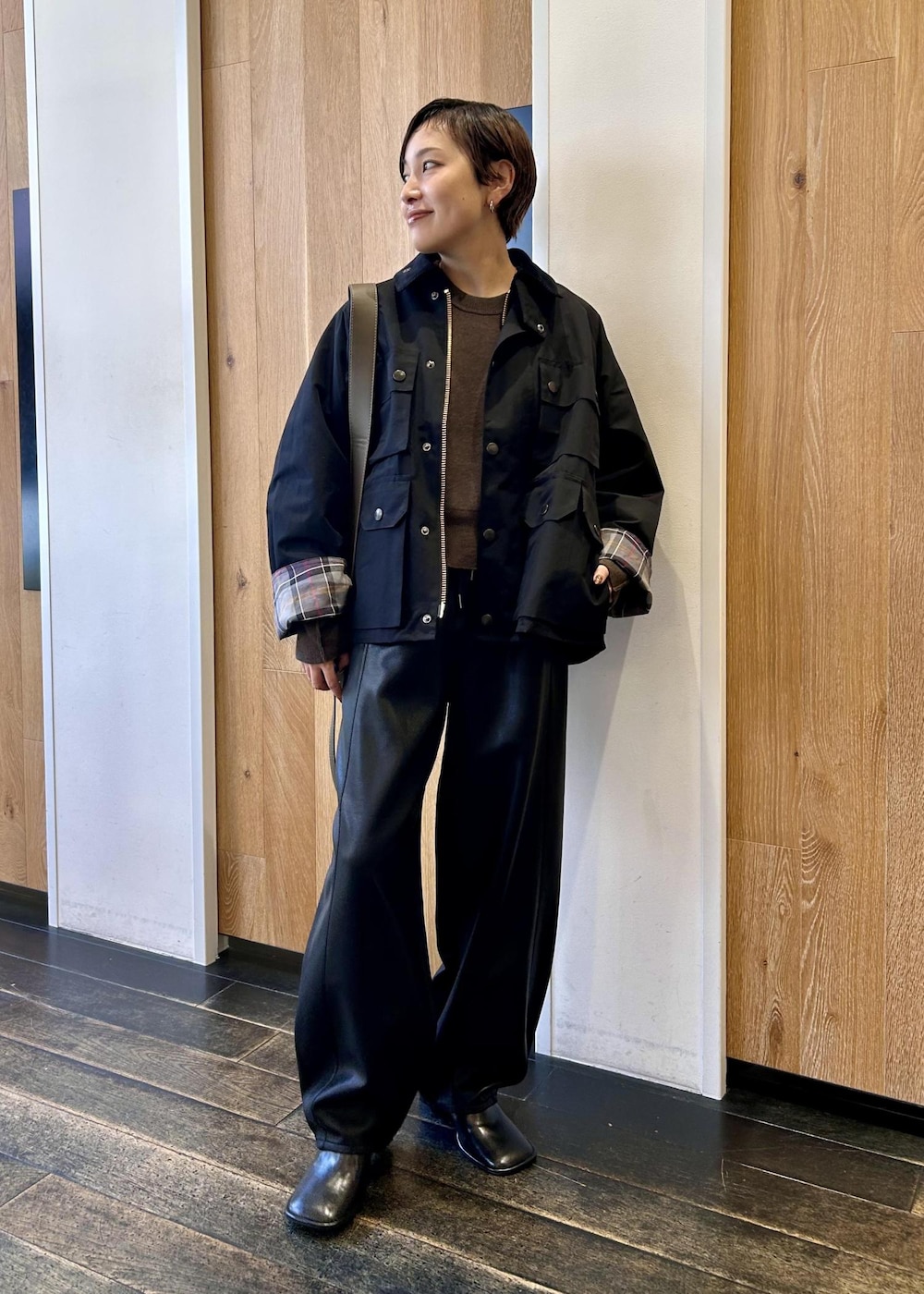 グリーン系のショルダーバッグ、ブラック系のブルゾン、ブラウン系のニット/セーターを着用したレディースの秋コーディネートの2枚目の写真