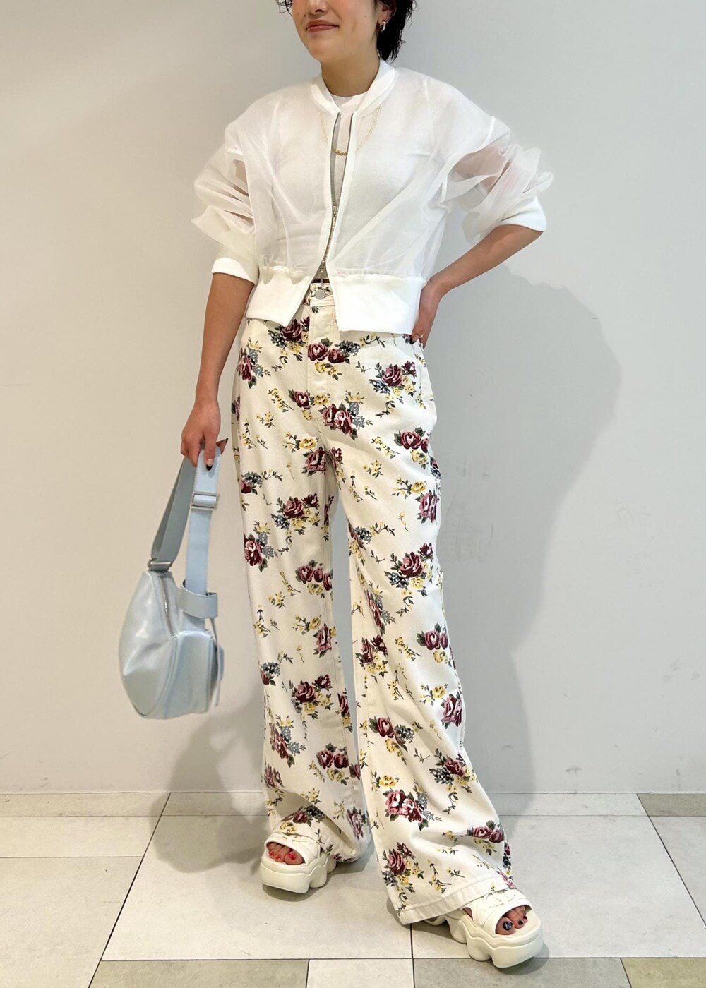 ブルー系のショルダーバッグ、ホワイト系のカーディガン/ボレロ、ベージュ系のデニムパンツを着用したレディースの春コーディネートの2枚目の写真