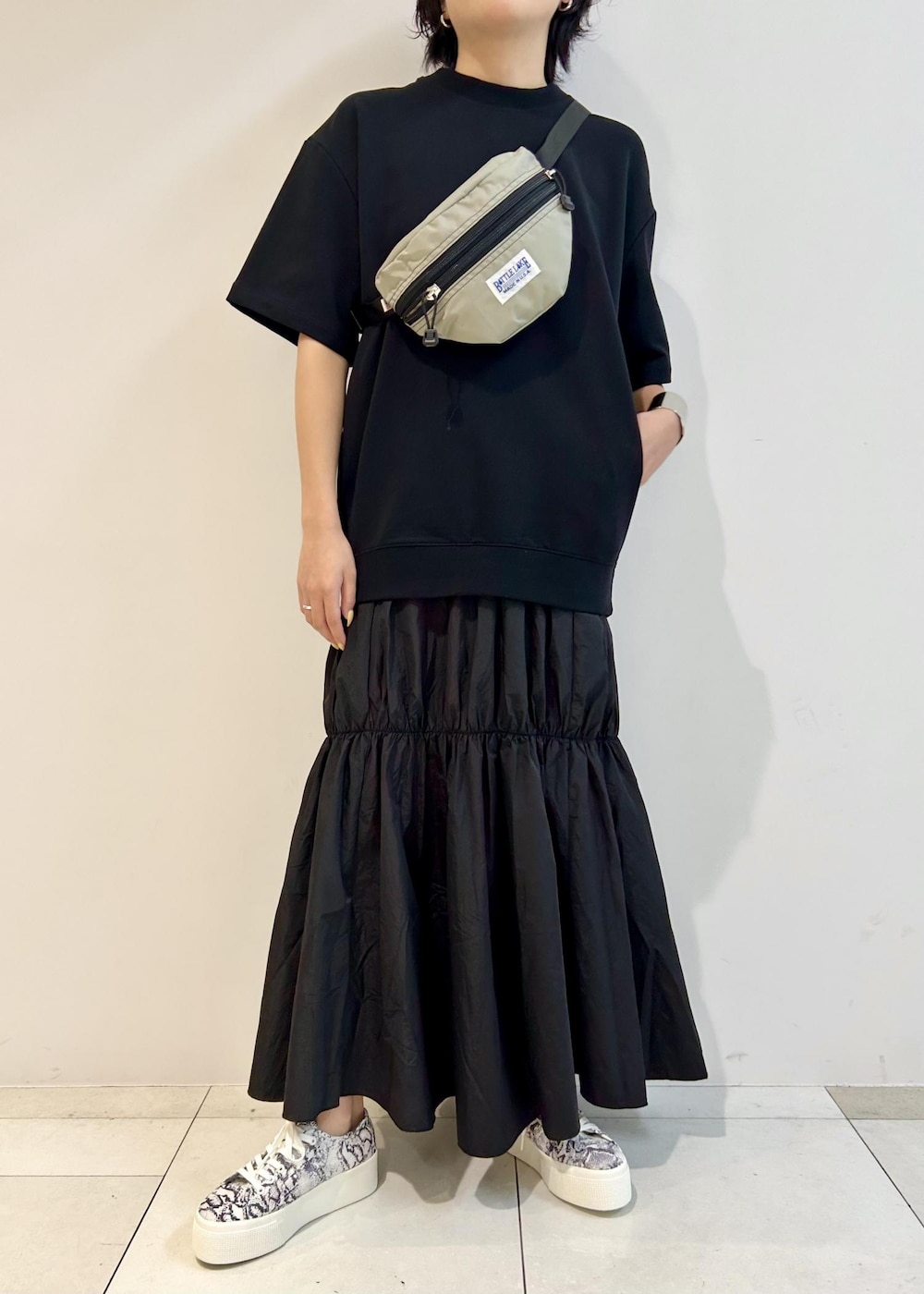 ブラック系のスニーカー、グレー系のボディバッグ/ウエストポーチ、ブラック系のワンピースを着用したレディースの夏コーディネートの7枚目の写真