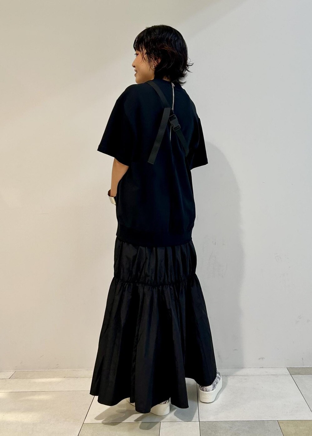 ブラック系のスニーカー、グレー系のボディバッグ/ウエストポーチ、ブラック系のワンピースを着用したレディースの夏コーディネートの2枚目の写真