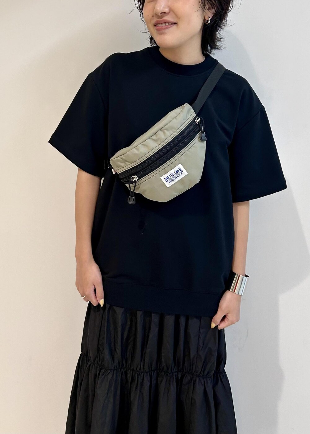 ブラック系のスニーカー、グレー系のボディバッグ/ウエストポーチ、ブラック系のワンピースを着用したレディースの夏コーディネートの5枚目の写真